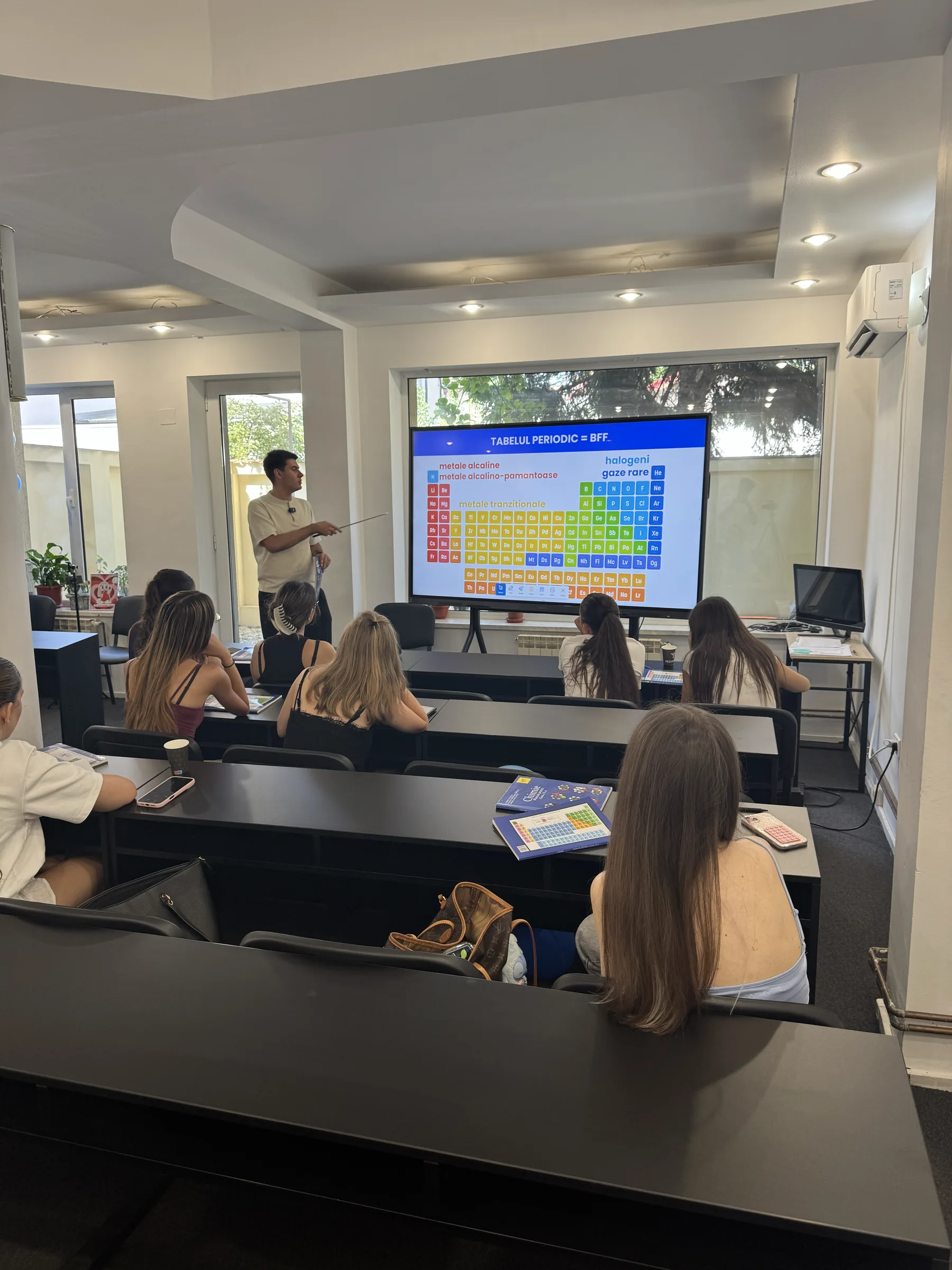 Curs în desfășurare: profesorul explică tabelul periodic pe ecranul mare