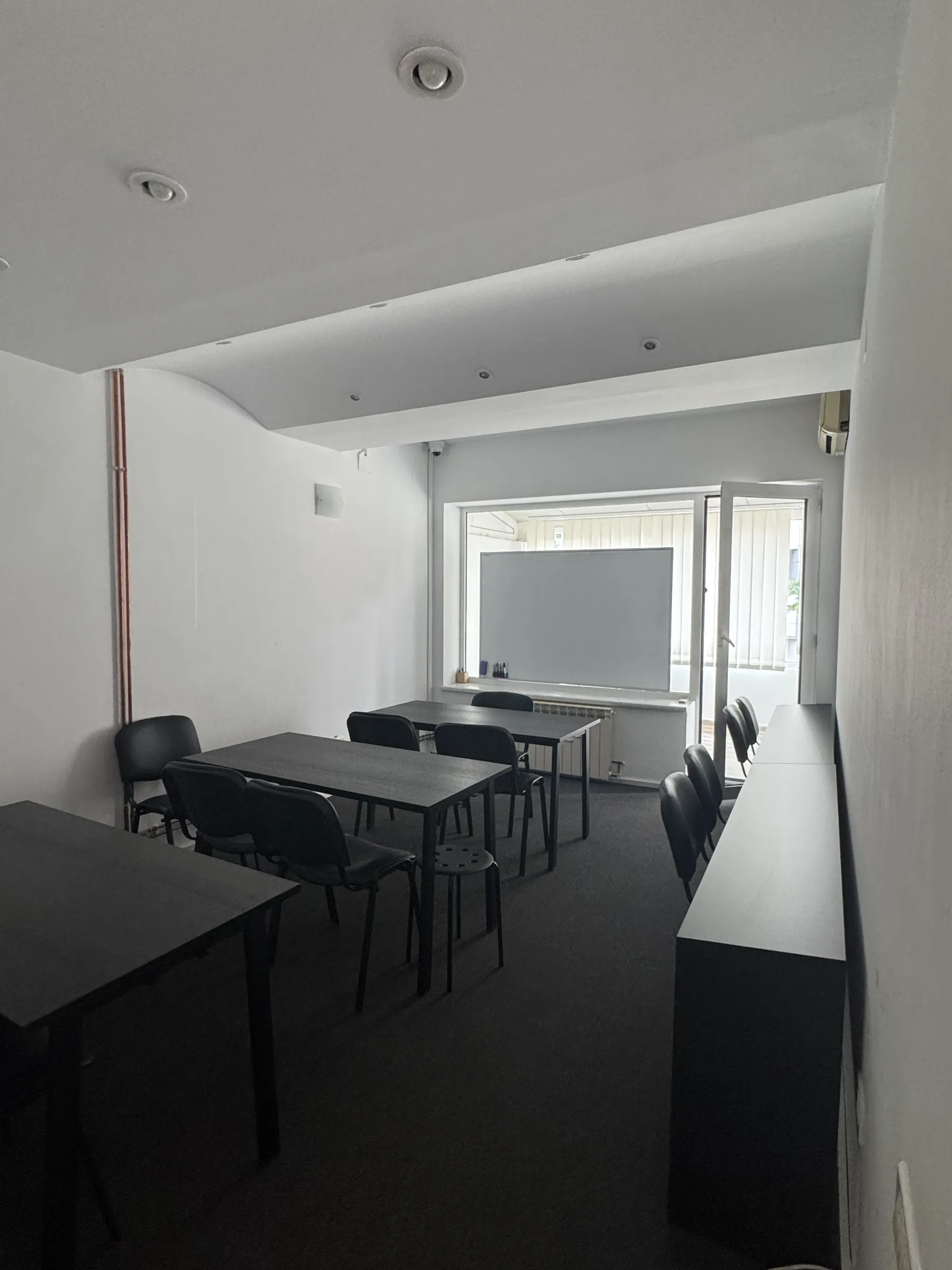 Sala 1 privită dinspre ușă, cu mesele în mijloc și tabla albă în fundal