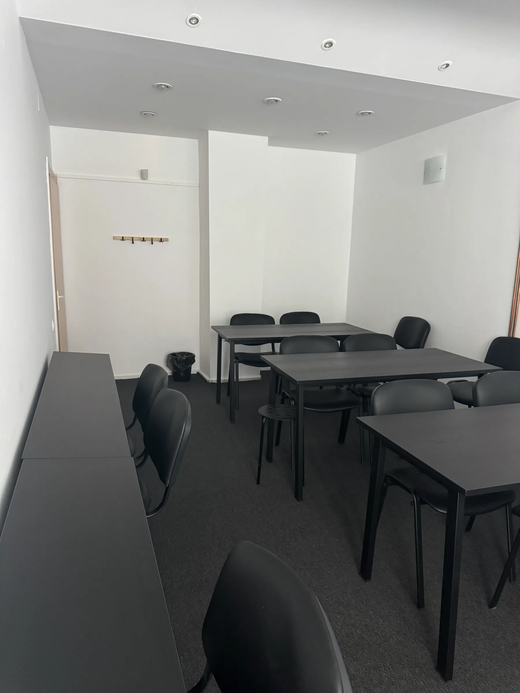 Sala 1 din celălalt colț, cu mesele grupate și biroul lung pe stânga
