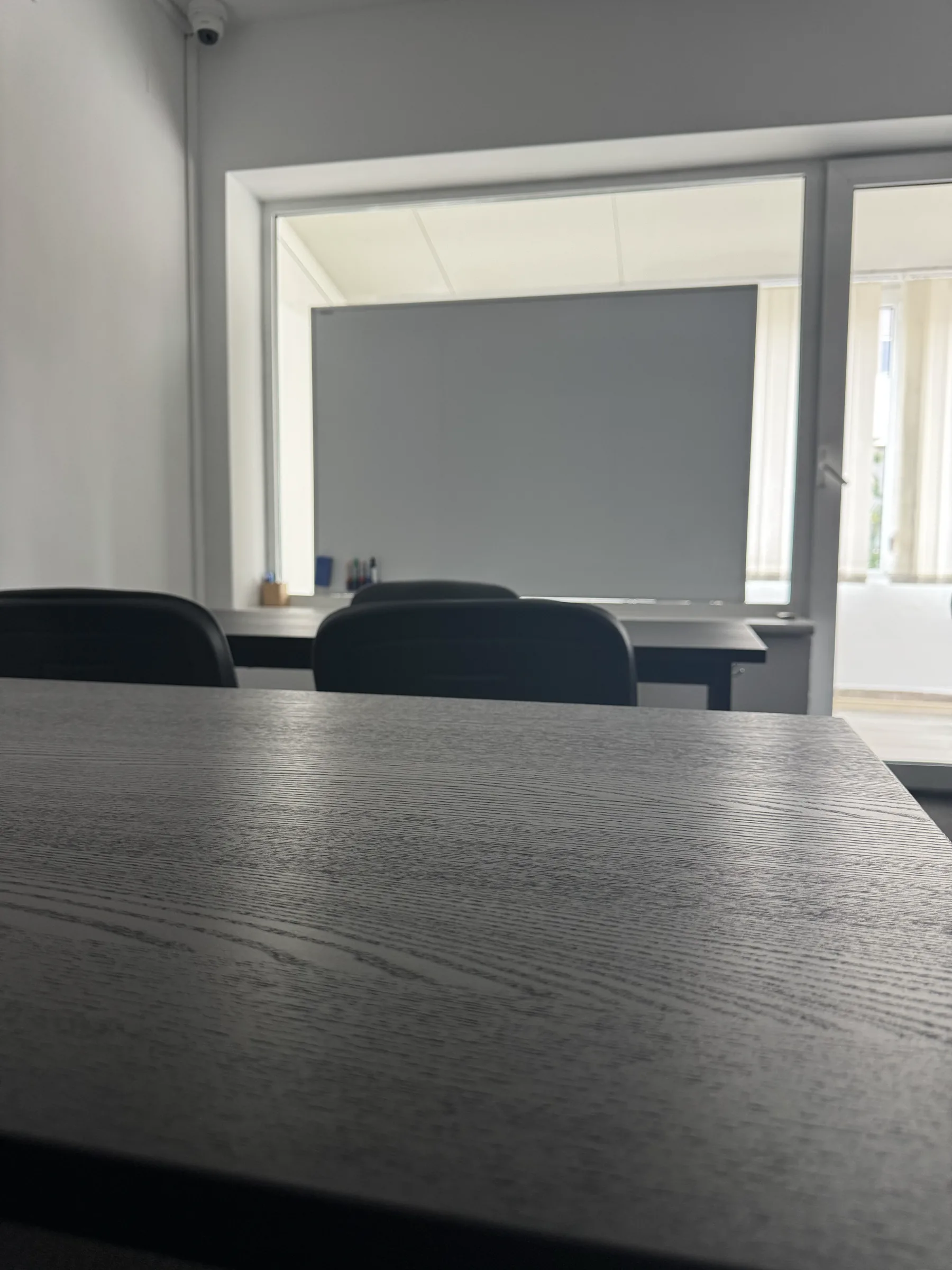 Detaliu cu blatul unei mese din Sala 1 și tabla albă în spate
